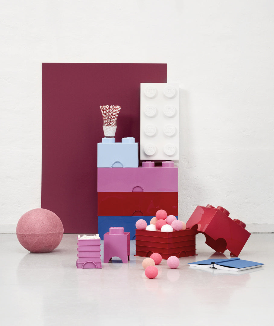 Biały pojemnik LEGO Brick 8 biały stojący na kolorowych pojemnikach w różnych odcieniach różu i czerwieni
