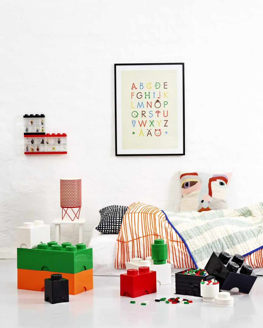 Pojemnik LEGO czarny obok kolorowych pudełek klocków LEGO w jasnym pokoju dziecięcym