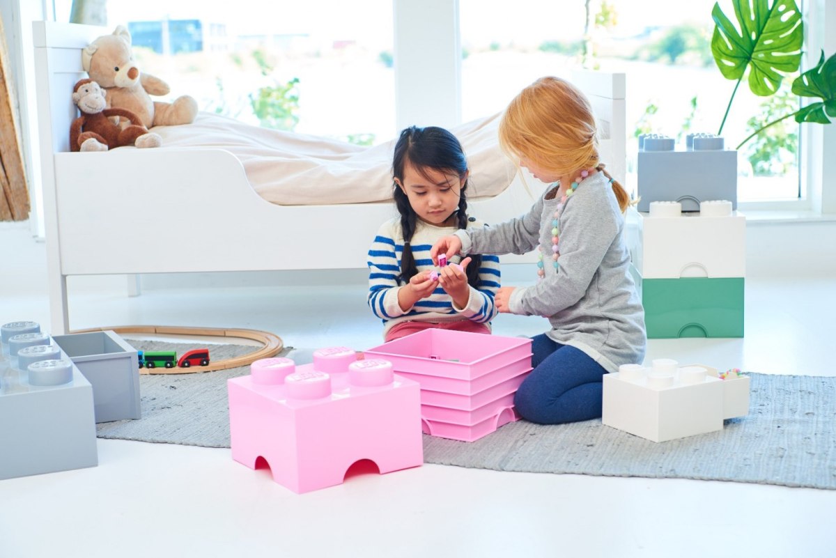 Dzieci bawiące się w pokoju z jasnoróżowym pojemnikiem LEGO Brick 4 do przechowywania klocków