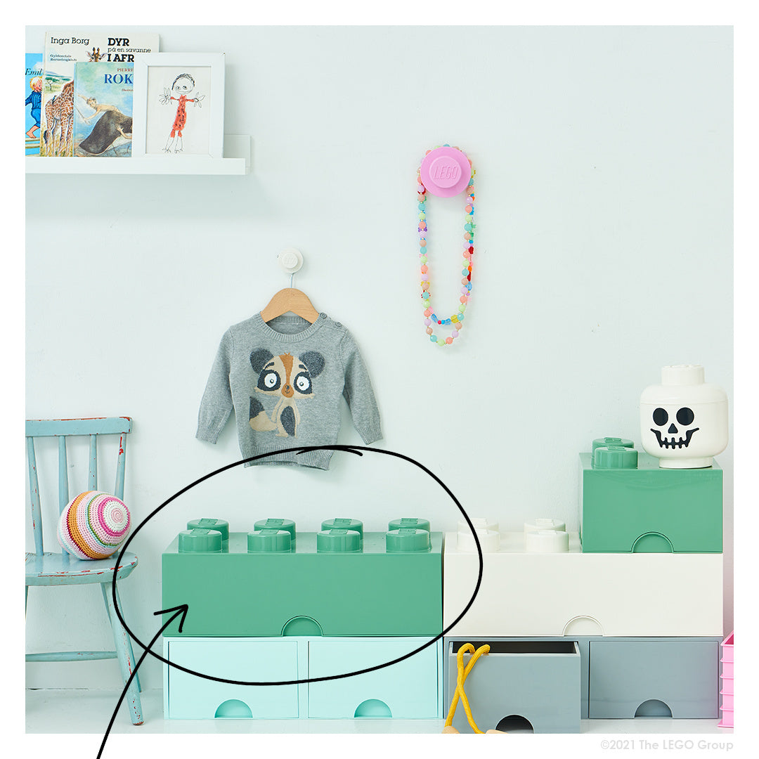 Zielony pojemnik LEGO na zabawki w kształcie klocka na tle pokoju dziecięcego