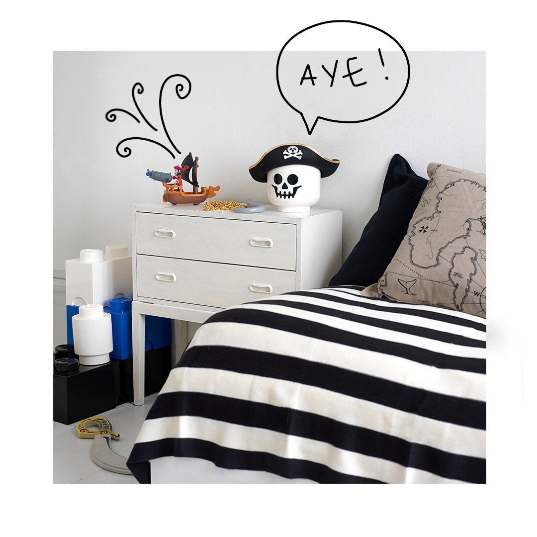 Pojemnik LEGO na zabawki w kształcie pirackiej głowy na stoliku nocnym w dziecięcym pokoju