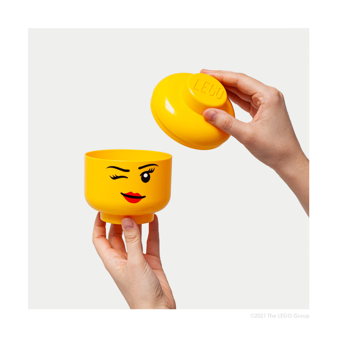 żółty pojemnik LEGO głowa dziewczynka z zamknięciem w kształcie klocka trzymany w dłoniach