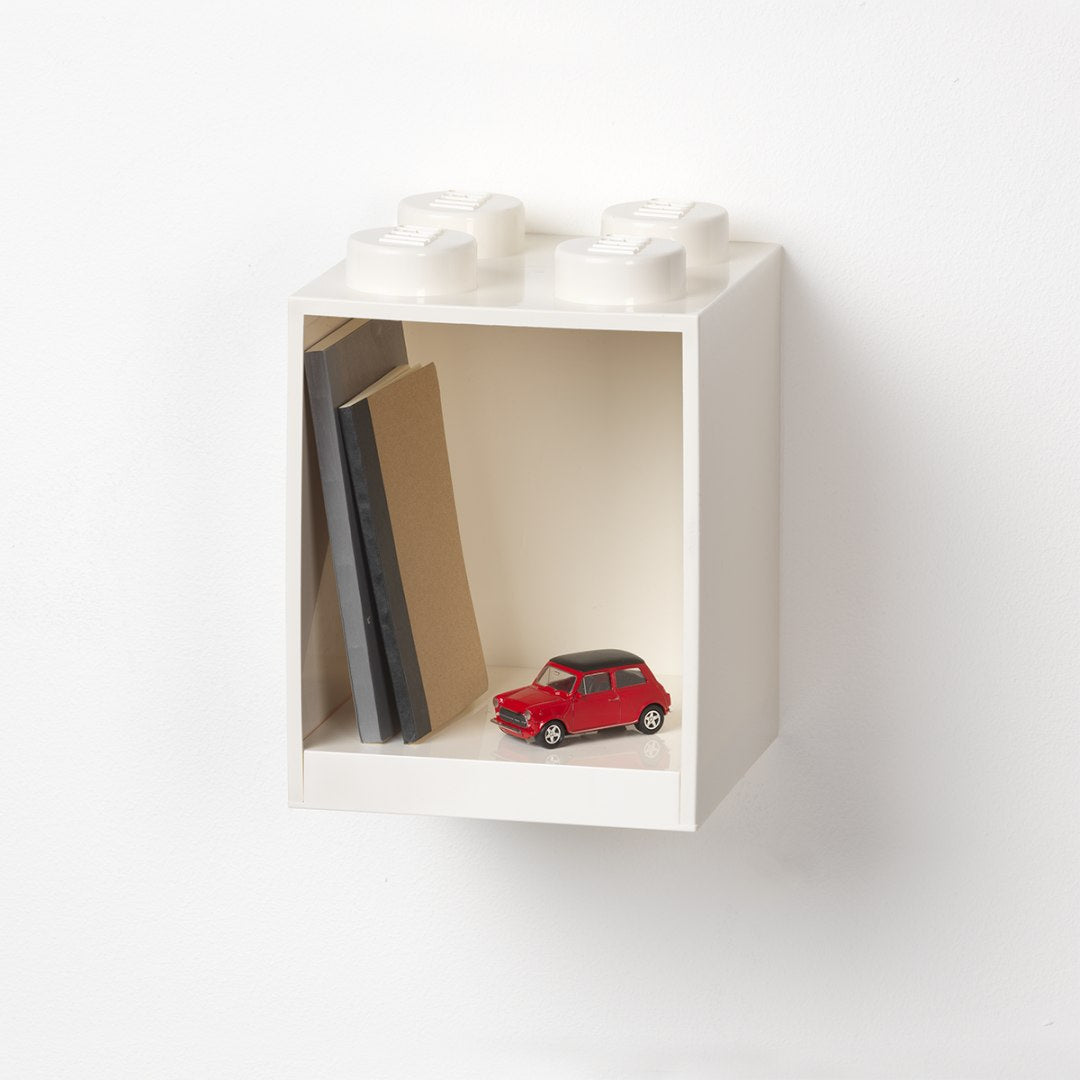 biała półka LEGO Brick 4 biała na ścianę z imitacją klocków LEGO na górze z książkami i czerwoną miniaturą auta