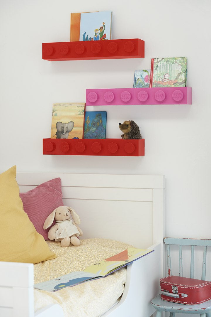 Kolorowe półki w stylu LEGO na ścianie z książkami i zabawkami obok łóżka dziecięcego czarna półka LEGO