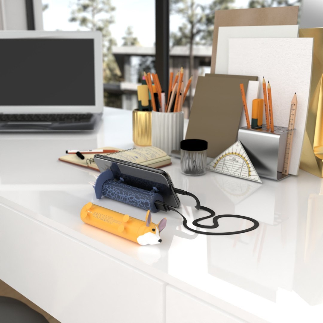 Yamann powerbank piesek corgi w kształcie psa na biurku obok smartfona podczas ładowania