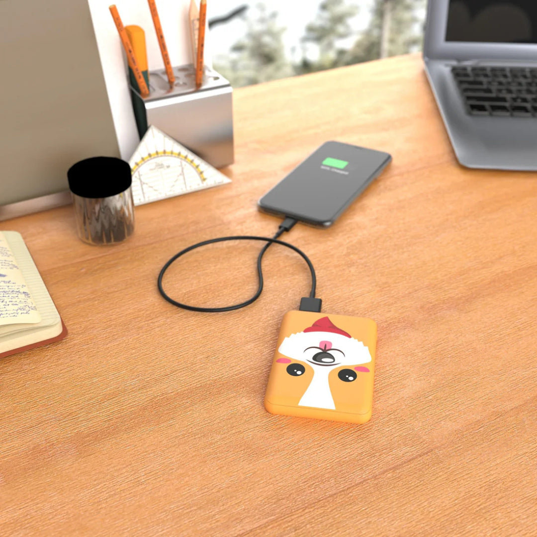 Powerbank piesek corgi Yamann na biurku podłączony do smartfona do ładowania urządzenia