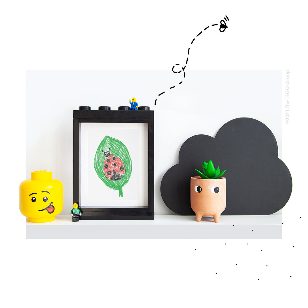 czarna ramka LEGO na zdjęcia czarna na białej półce z figurkami oraz rośliną doniczkową