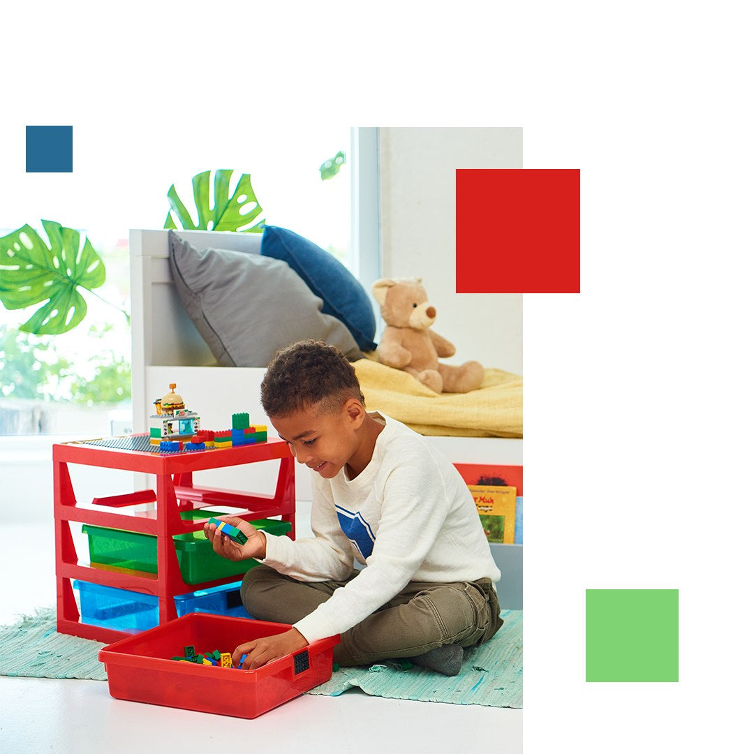 Dziecko bawiące się klockami LEGO przy czerwonym regale LEGO z szufladami w jasnym pokoju