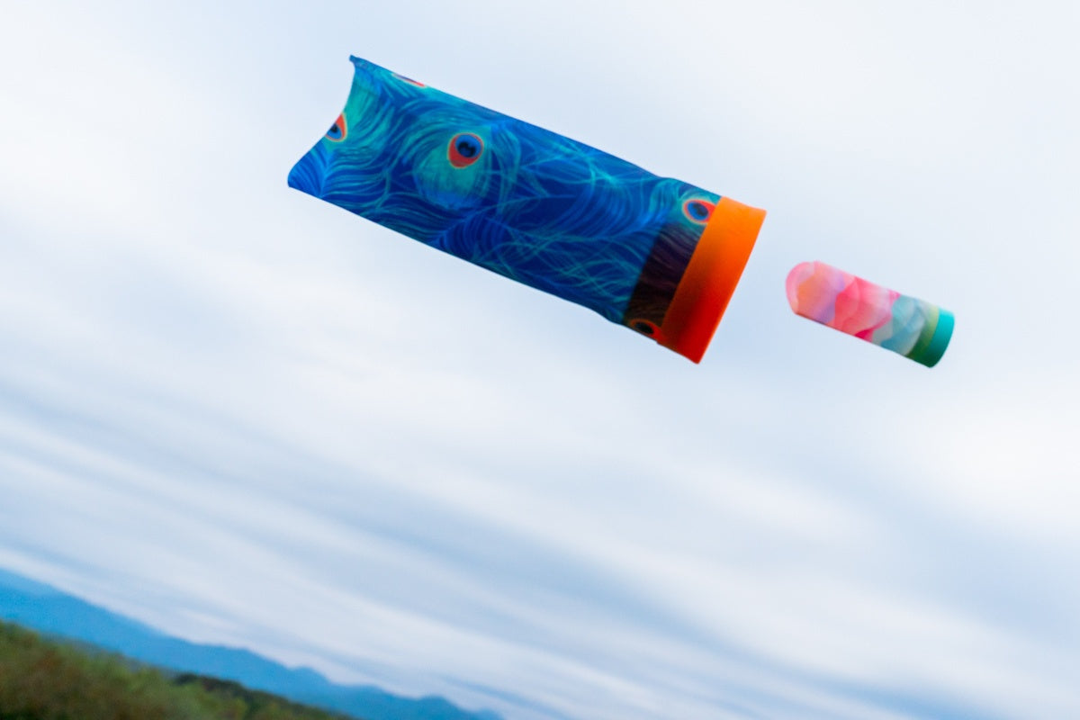 Rzutka Waboba Airlyft w niebieskim kolorze z wzorem pawich piór podczas lotu na tle nieba