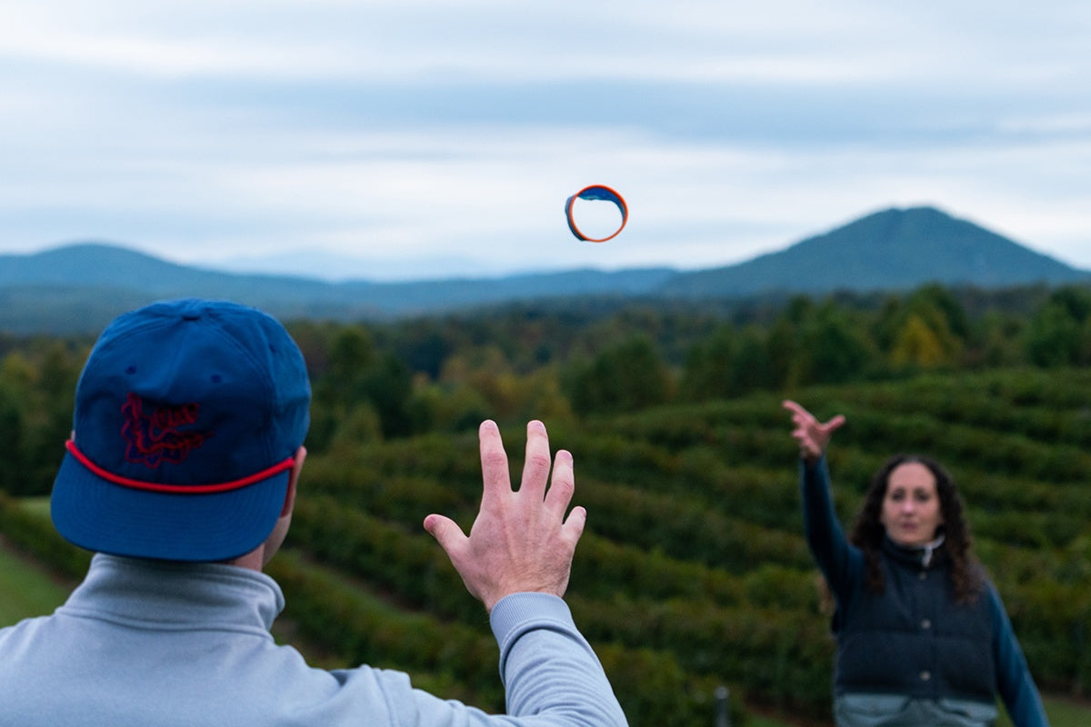 Osoby rzucają rzutką Waboba Airlyft na zewnątrz w górzystym terenie podczas aktywnej zabawy