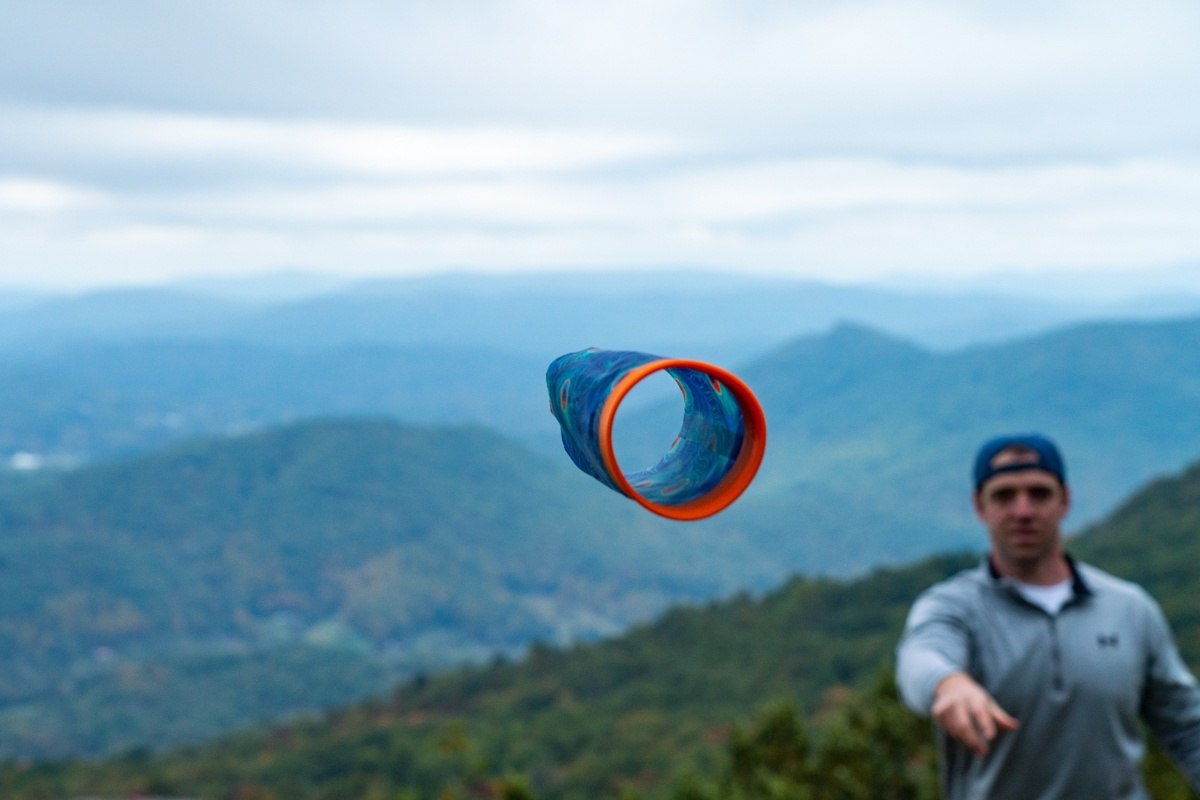 Mężczyzna rzucający zabawkę rzutka Waboba Airlyft dla dzieci na tle górskiego krajobrazu