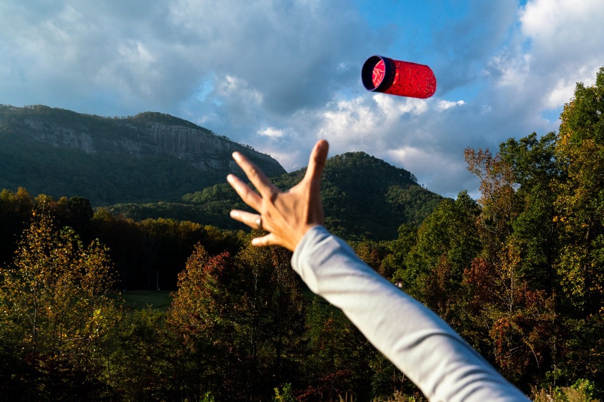 Rzutka Waboba Airlyft czerwona w locie rzucana na tle gór i lasu podczas słonecznego dnia