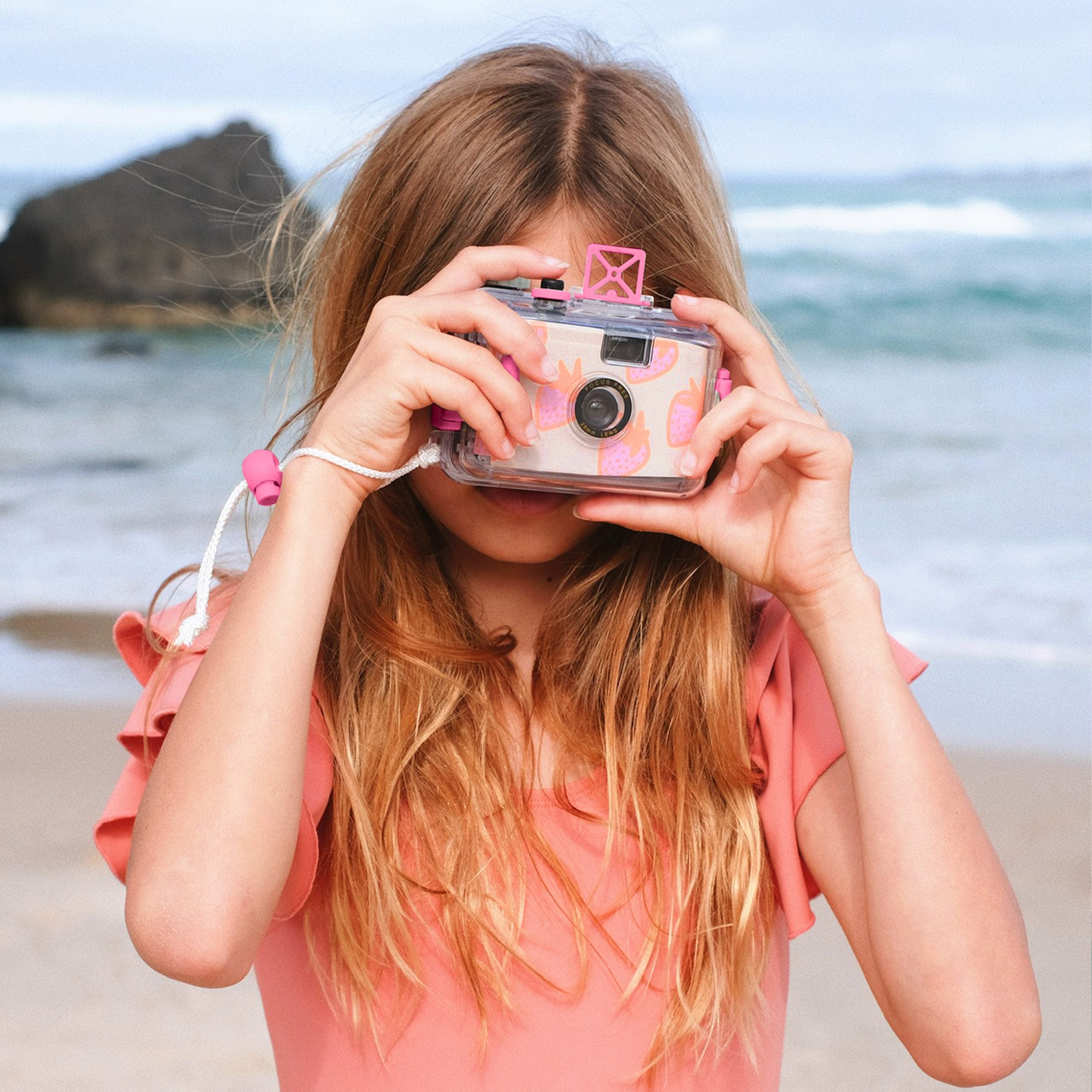 Podwodny aparat analogowy dla dzieci marki Sunny Life trzymany przez dziewczynkę na plaży