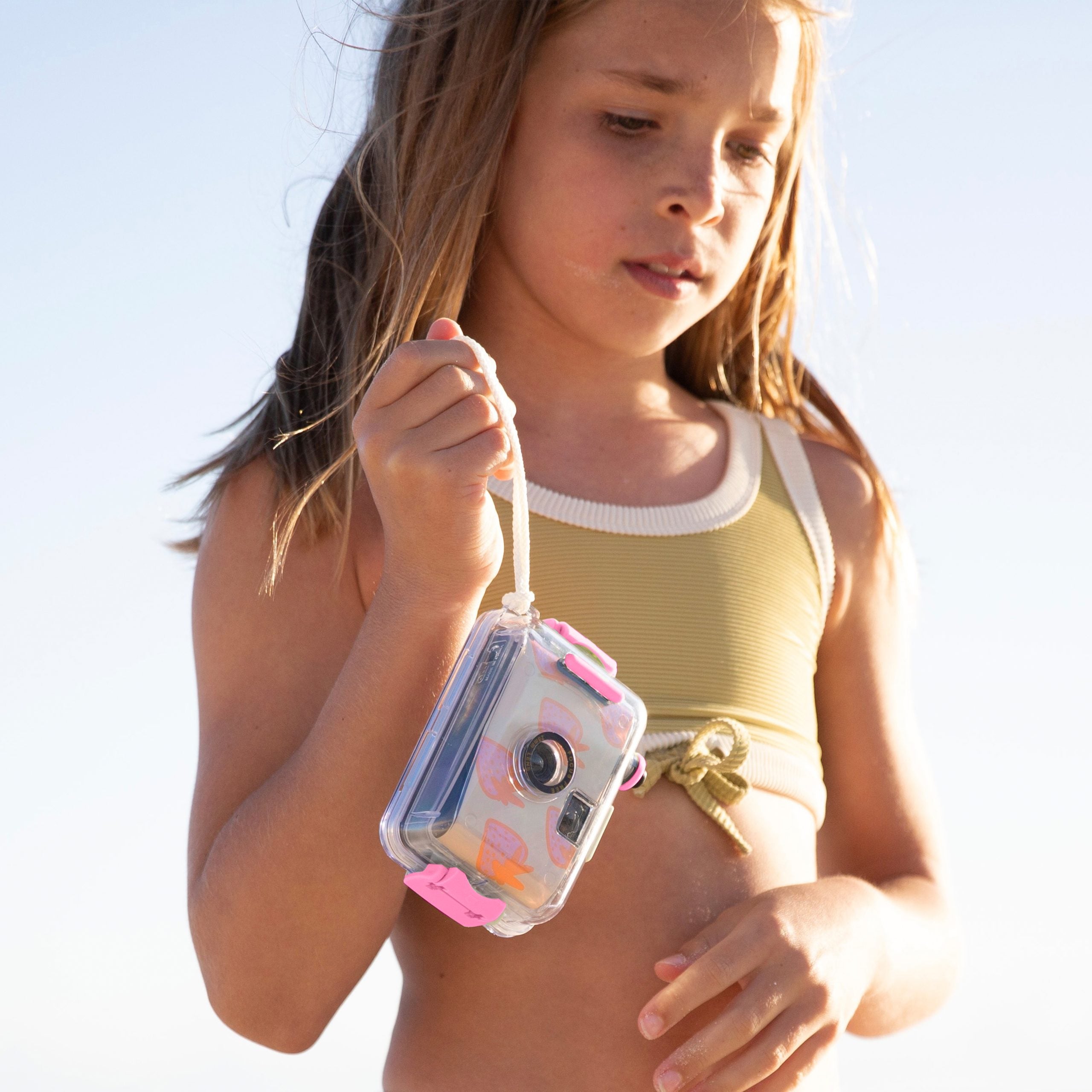 Podwodny aparat analogowy dla dzieci marki Sunny Life trzymany przez dziewczynkę na plaży