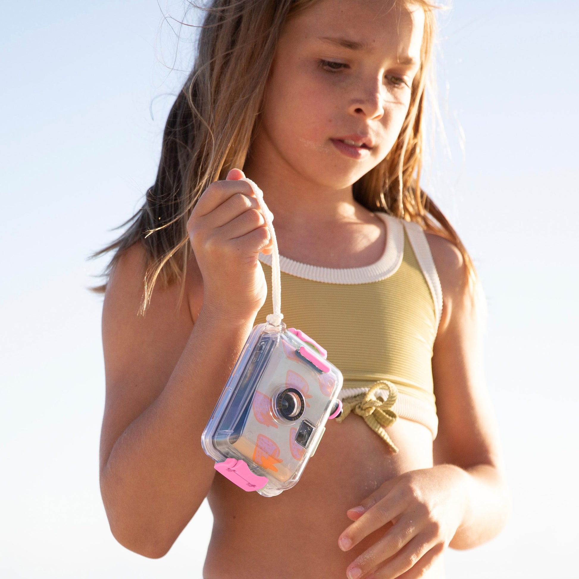 Podwodny aparat analogowy dla dzieci marki Sunny Life trzymany przez dziewczynkę na plaży