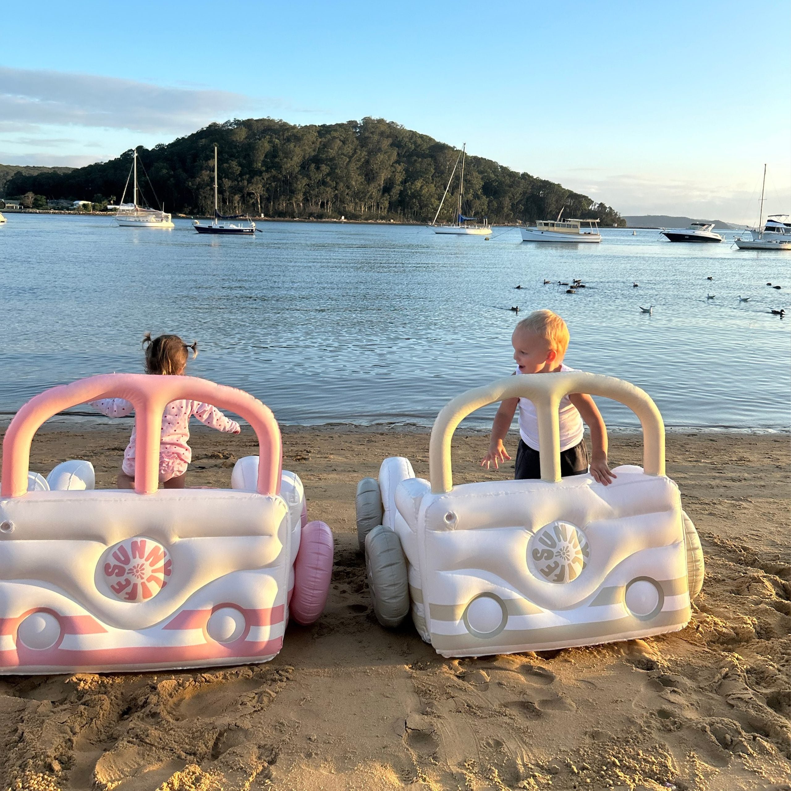 LOQI dmuchane łóżko dziecięce samochód w różowym i białym kolorze na plaży z dziećmi