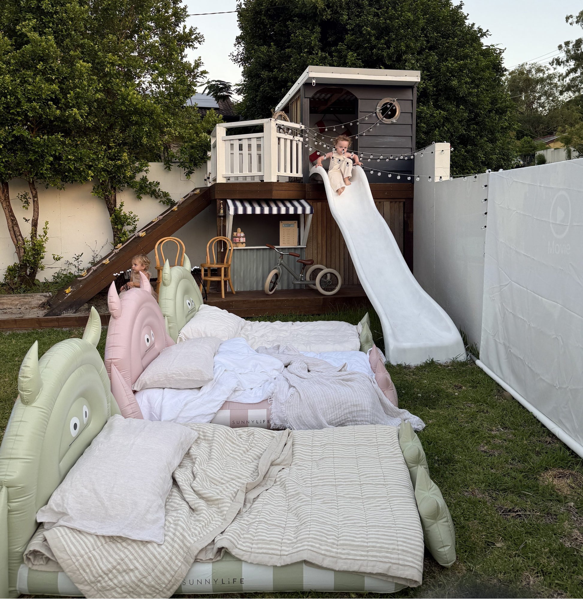 Dmuchane łóżko dla dzieci od LOQI w kształcie zwierząt z pościelą na trawniku obok placu zabaw