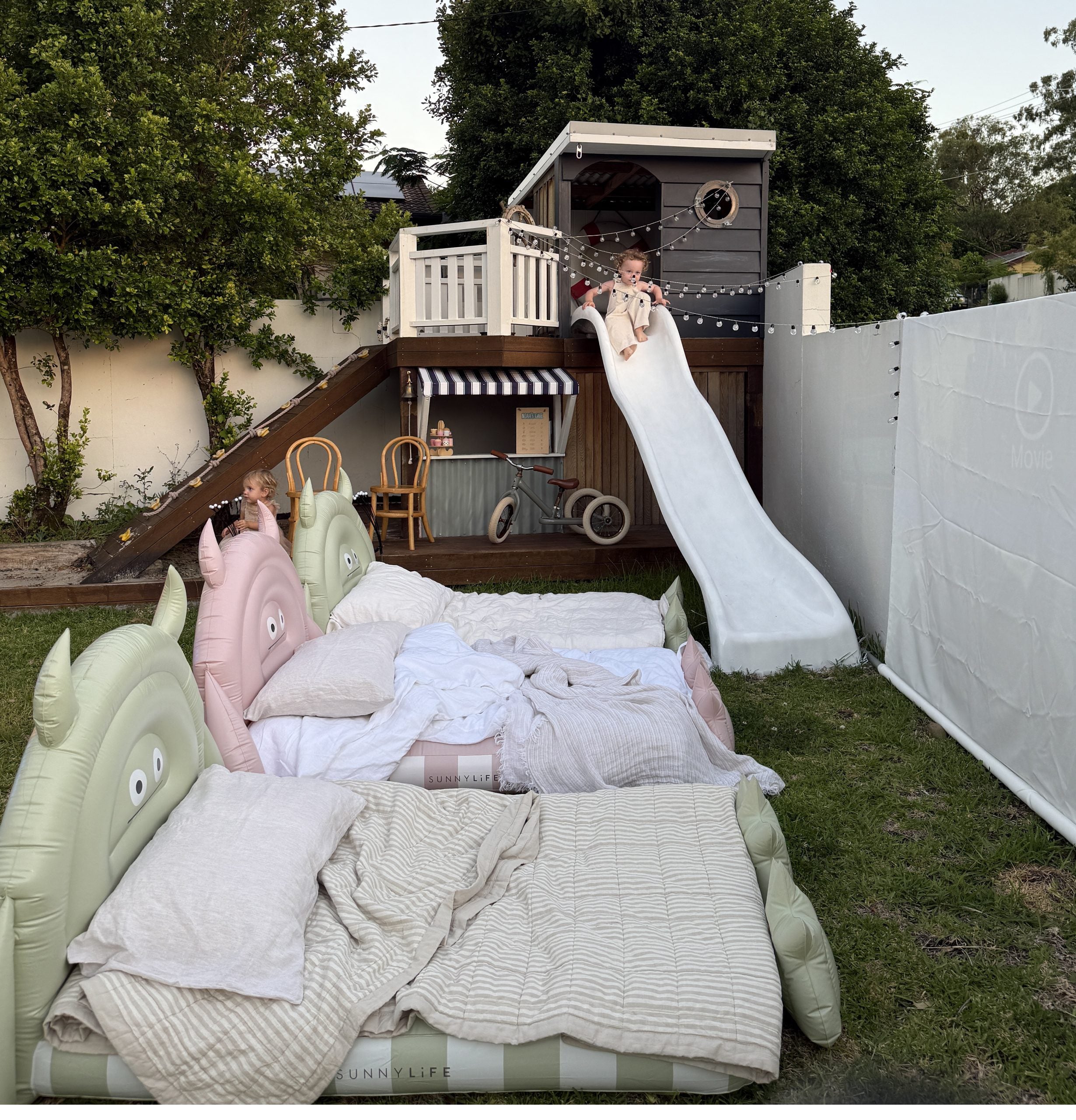 Dmuchane łóżko dla dzieci od LOQI w kształcie zwierząt z pościelą na trawniku obok placu zabaw