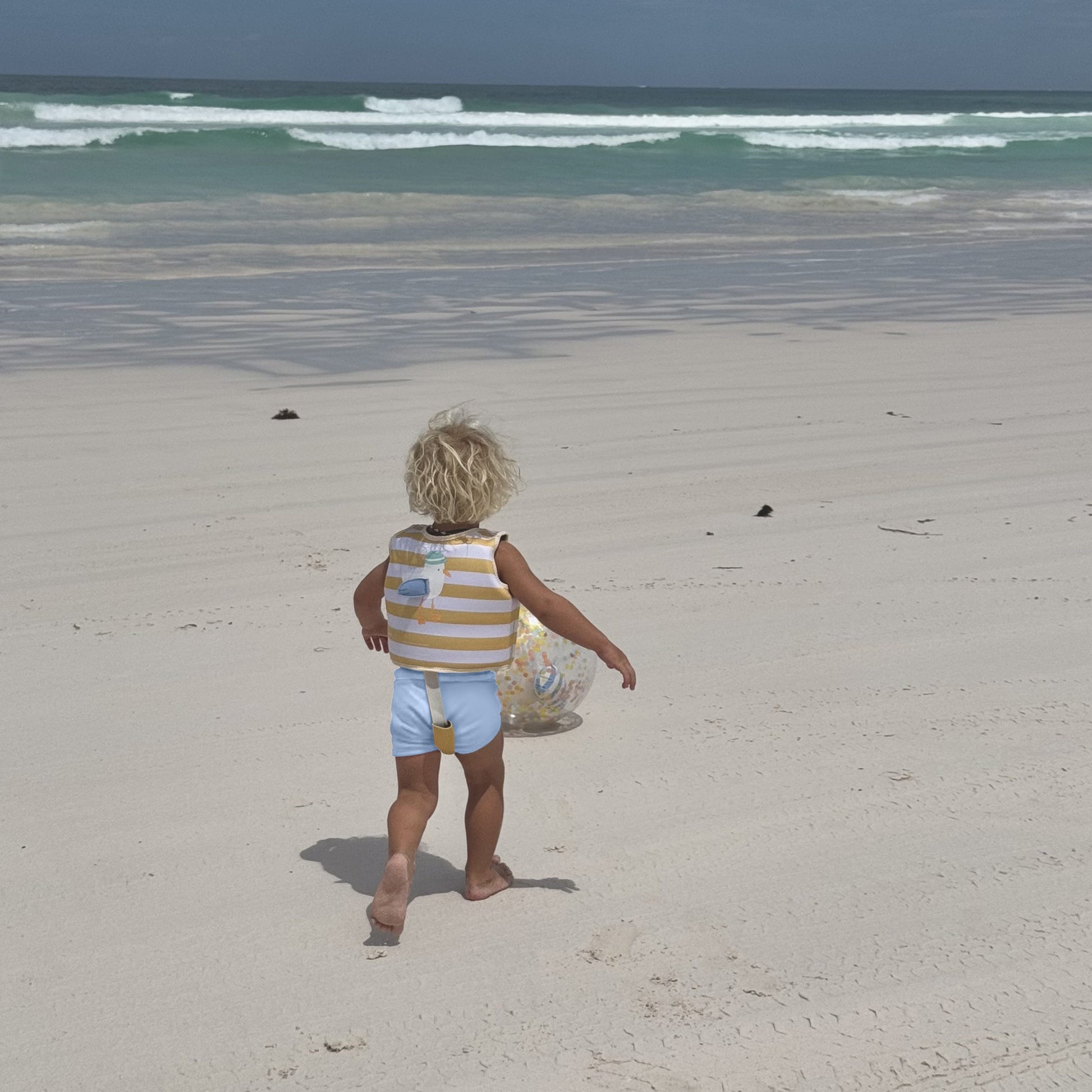 Dziecko na plaży w kamizelce do pływania dla dzieci 2-3 lata marki LOQI z pasami ochronnymi