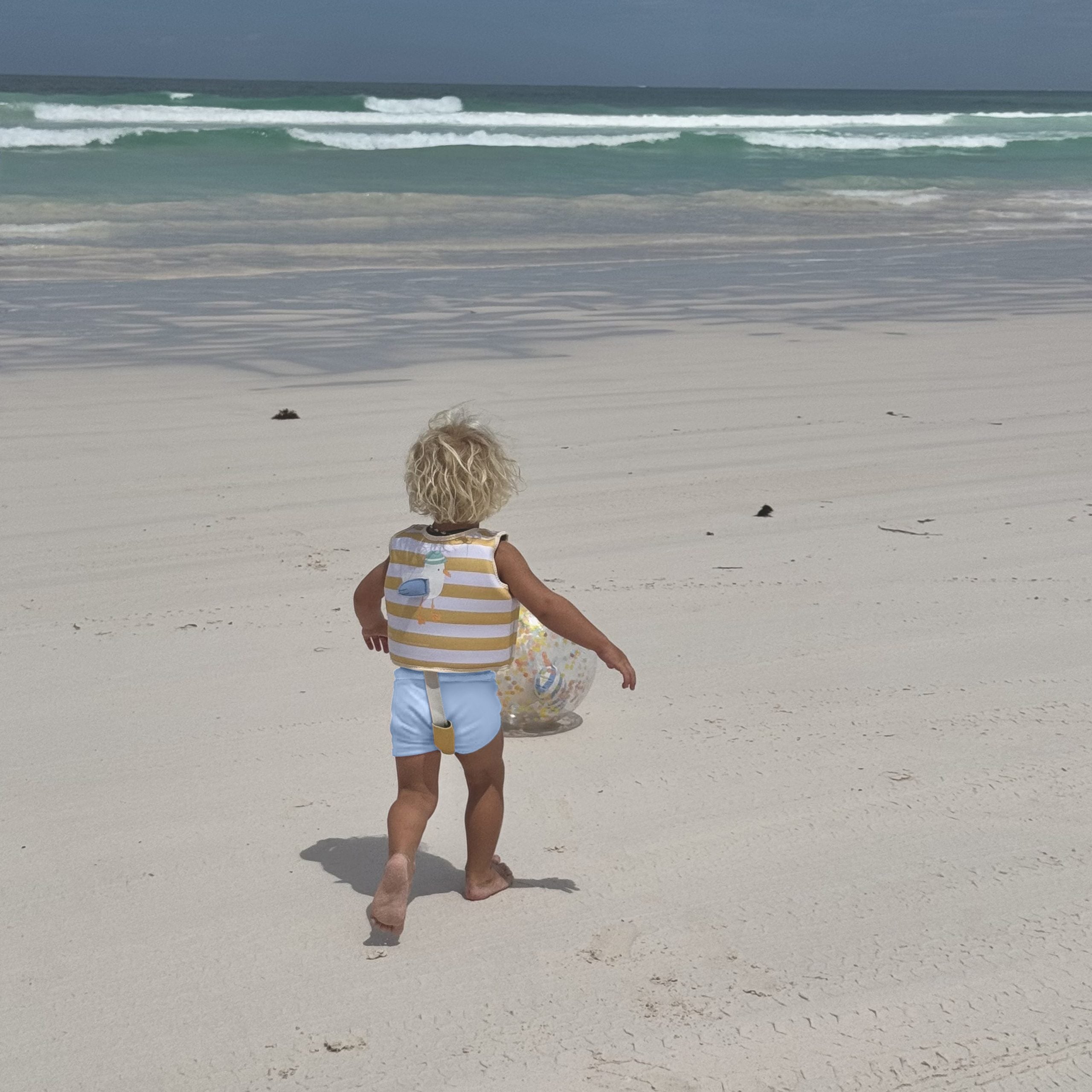 Dziecko na plaży w kamizelce do pływania dla dzieci 2-3 lata marki LOQI z pasami ochronnymi