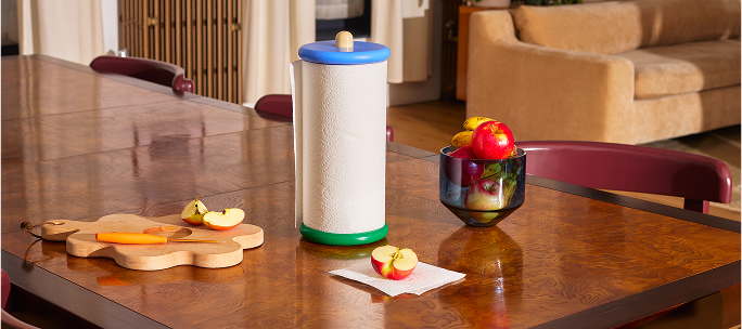 Uchwyt na ręcznik papierowy design Areaware na drewnianym stole w kuchni z owocami i deską do krojenia