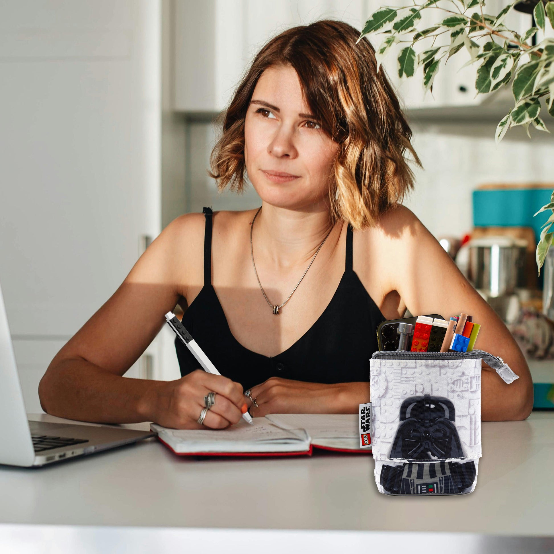 Piórnik LEGO Star Wars z motywem Dartha Vadera na biurku obok kobiety piszącej notatki