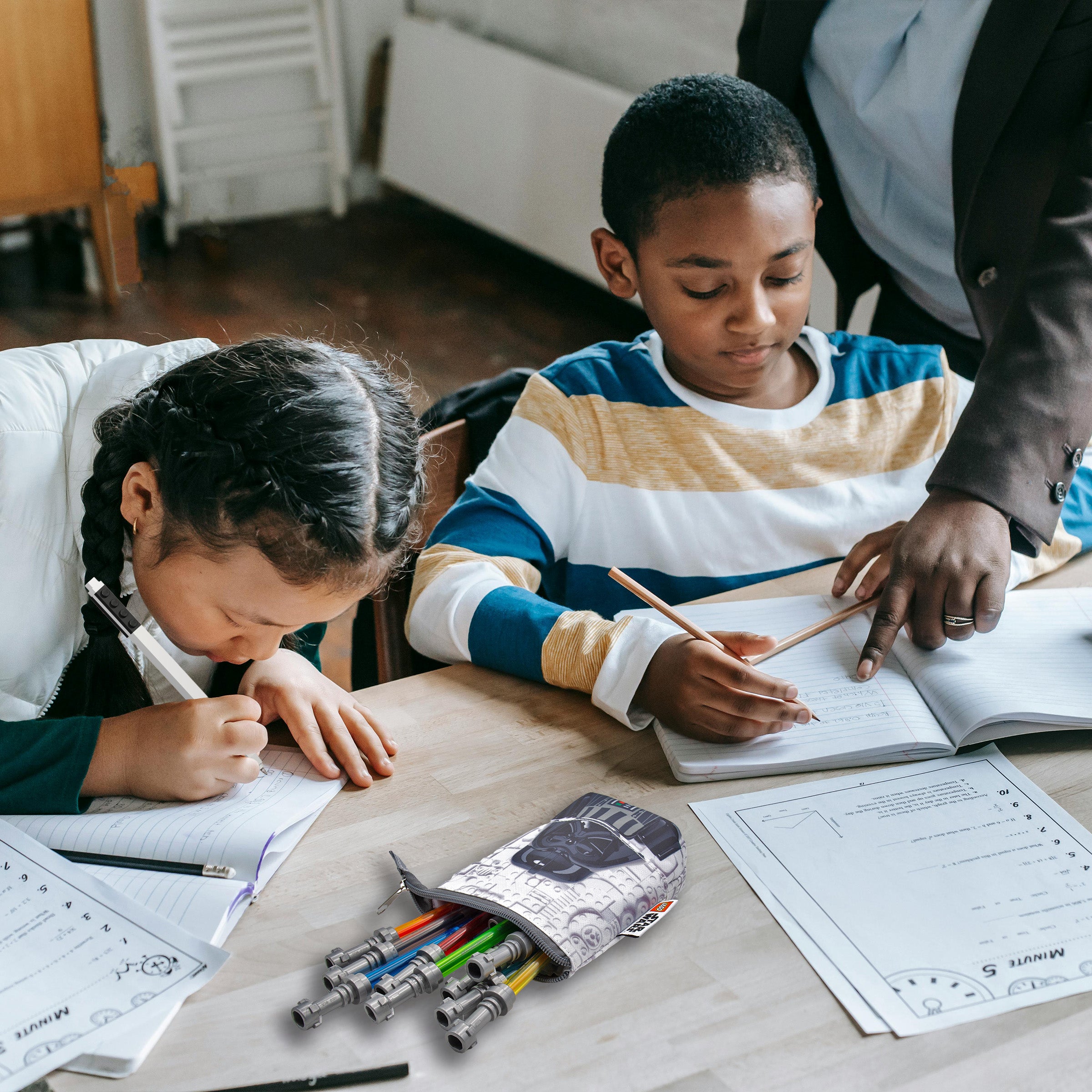 Dzieci uczące się przy stole z piórnikiem LEGO Star Wars wypełnionym długopisami i ołówkami