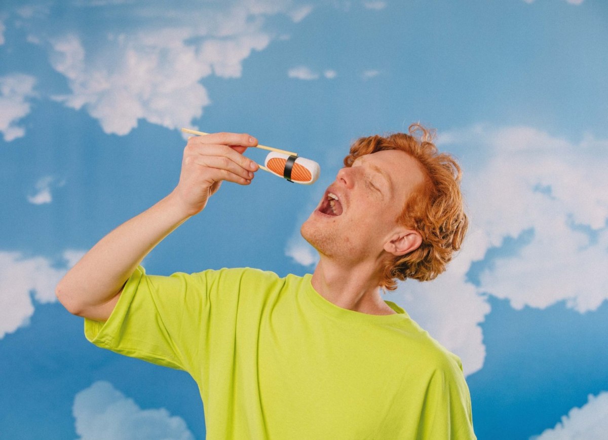 Mężczyzna w zielonej koszulce bawiący się zabawką sushi w kształcie rolki sushi do skarpetki skarpetki sushi box