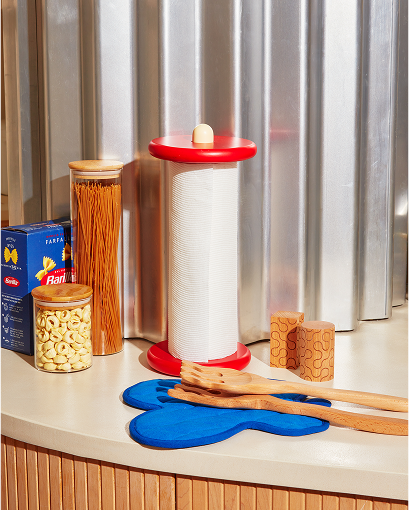 Czerwono-biały uchwyt na ręcznik papierowy design marki Areaware na kuchennym blacie obok akcesoriów