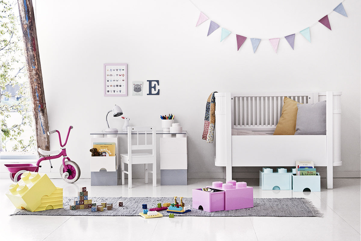 biały pokój dziecięcy z szufladą LEGO na zabawki w kształcie kolorowych klocków obok łóżeczka
