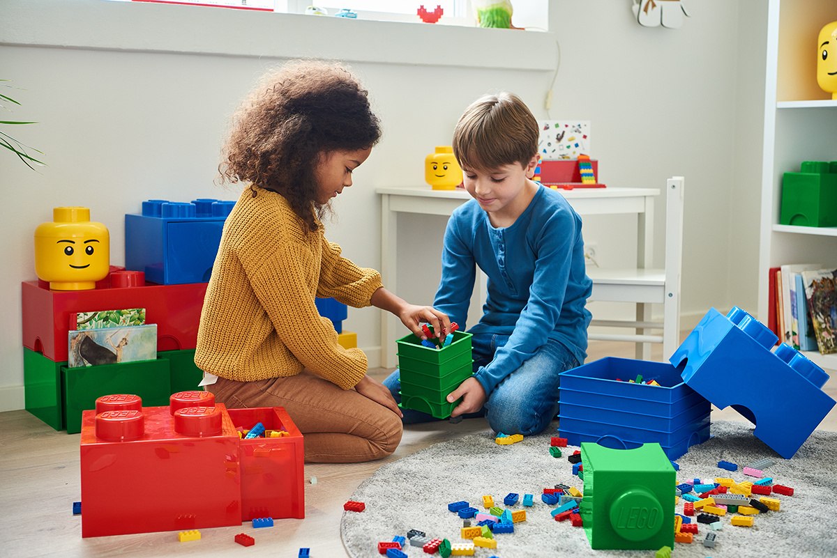 dwoje dzieci bawiących się klockami LEGO obok czerwonej szuflady LEGO Brick 4 czerwona pełnej kolorowych klocków