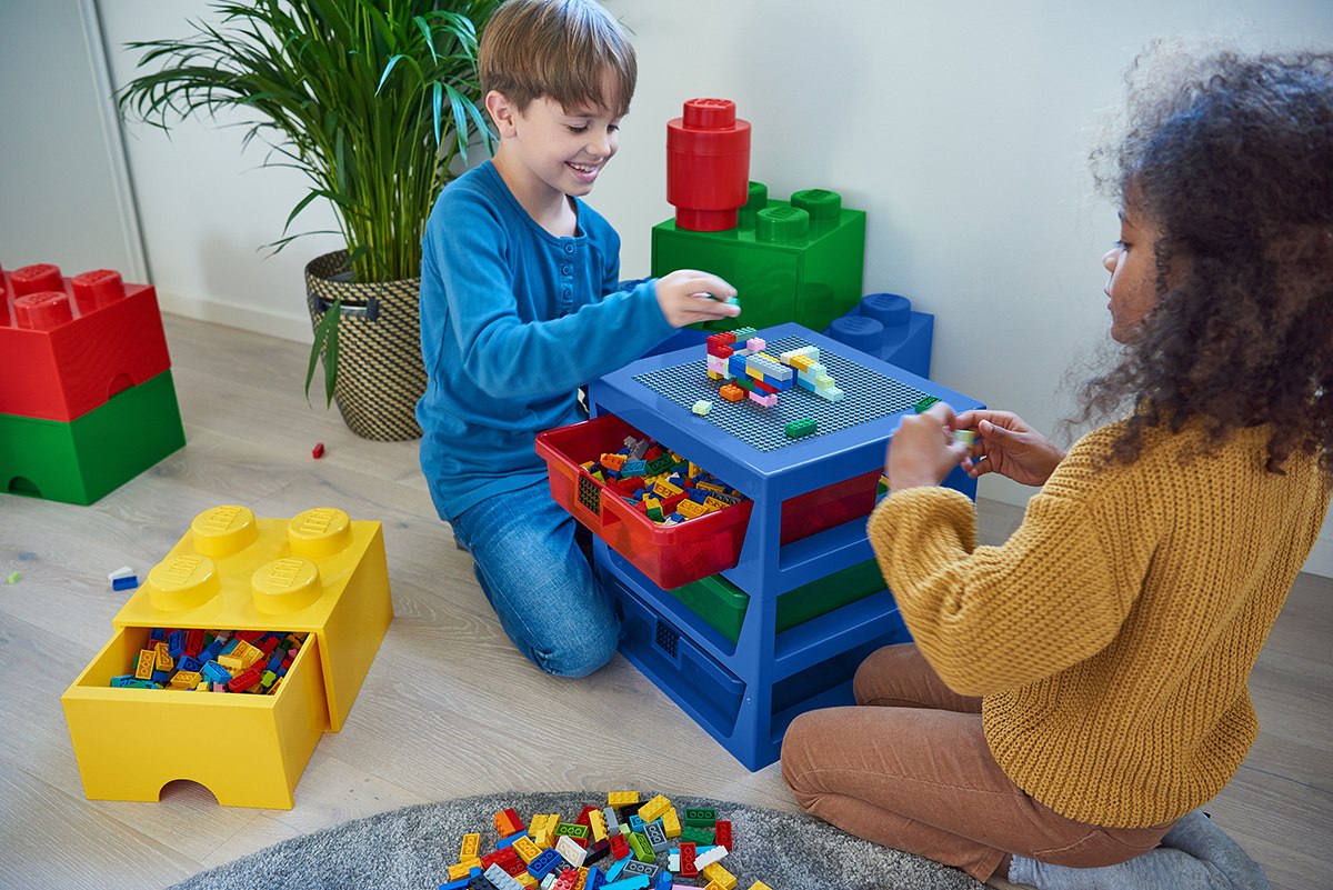 Dzieci bawiące się klockami LEGO przy niebieskim stole z szufladą LEGO Brick 4 zielona w pokoju zabaw