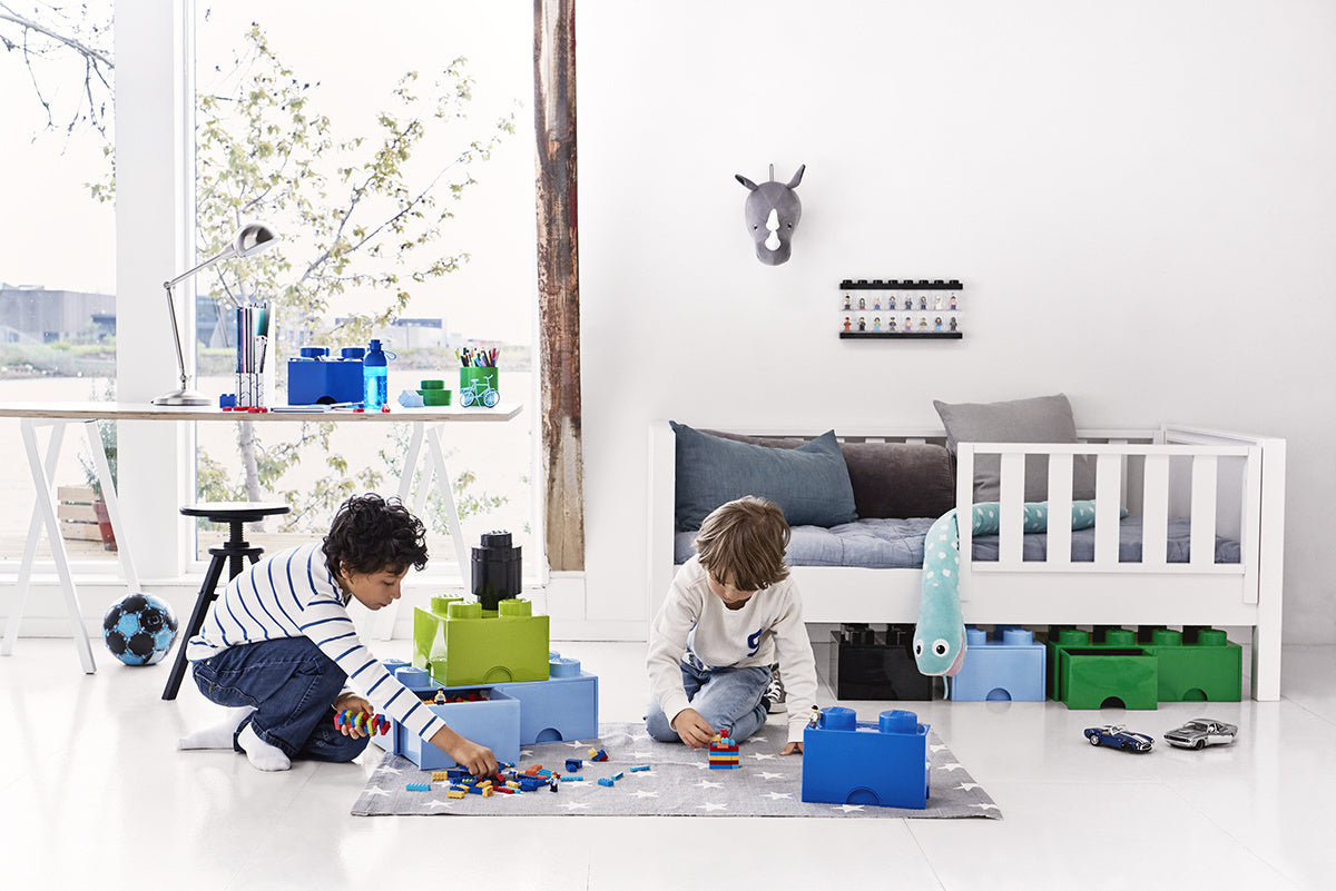 Dzieci bawiące się klockami obok szuflady LEGO na klocki w jasnym pokoju dziecięcym