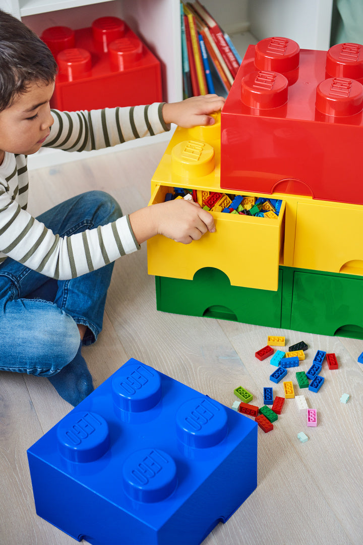 Chłopiec wyciąga klocki z zielonej szuflady LEGO Brick 8 zielona w zestawie kolorowych pudełek