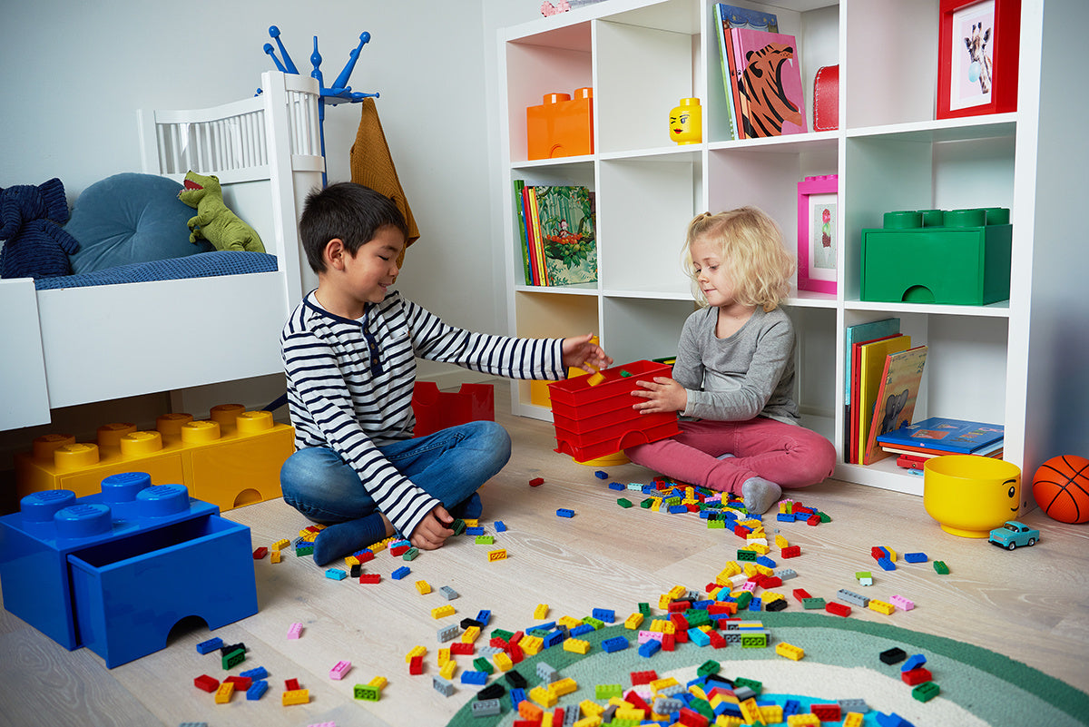 Dzieci bawiące się z żółtą szufladą LEGO Brick 8 w pokoju pełnym kolorowych klocków LEGO