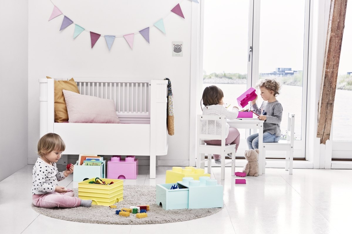 Dzieci bawiące się w jasnym pokoju z kolorową szufladą LEGO do przechowywania na klocki