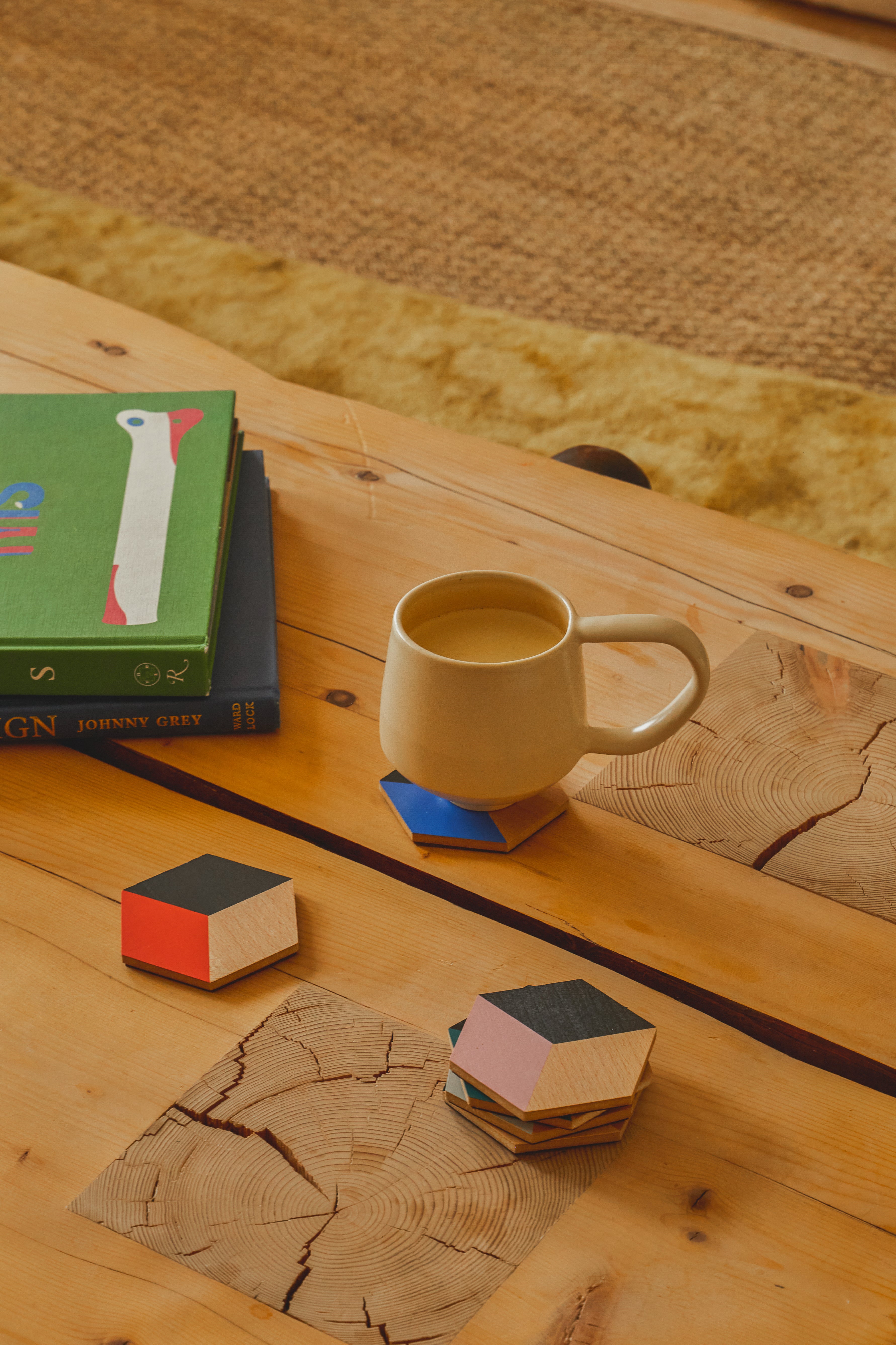 Nowoczesne podkładki stołowe nowoczesne Areaware pod kubek na drewnianym stole z książkami