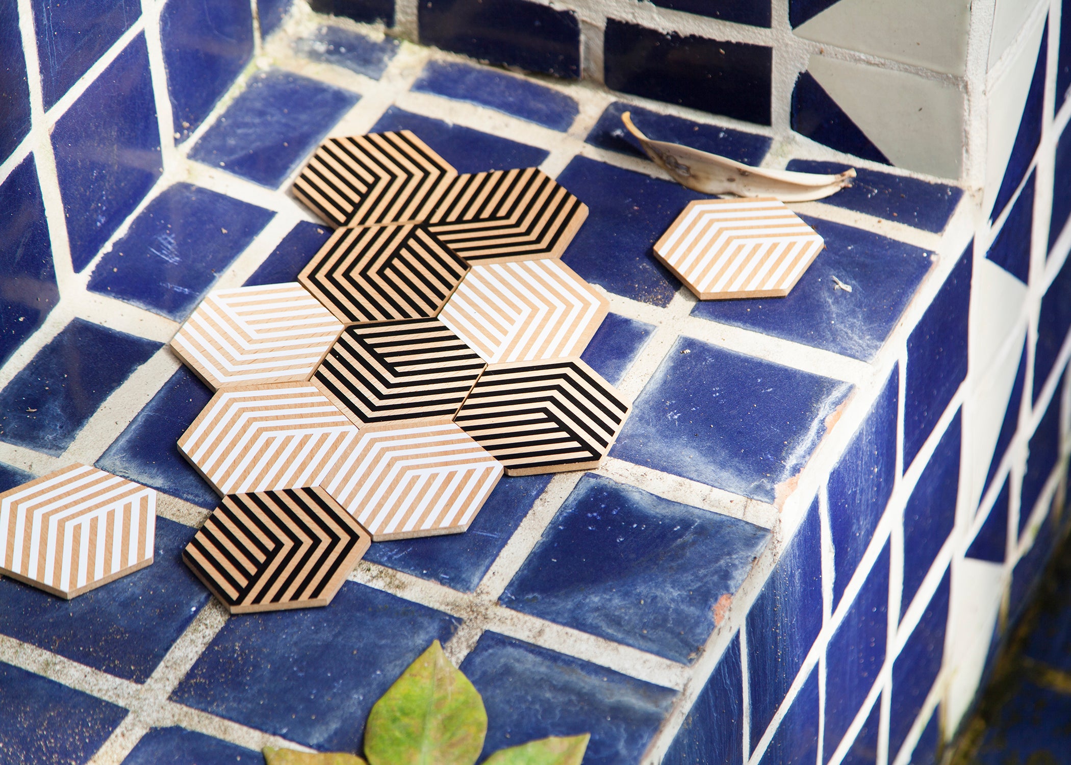 Podkładki stołowe czarne design w geometryczne wzory ułożone na niebieskich kafelkach