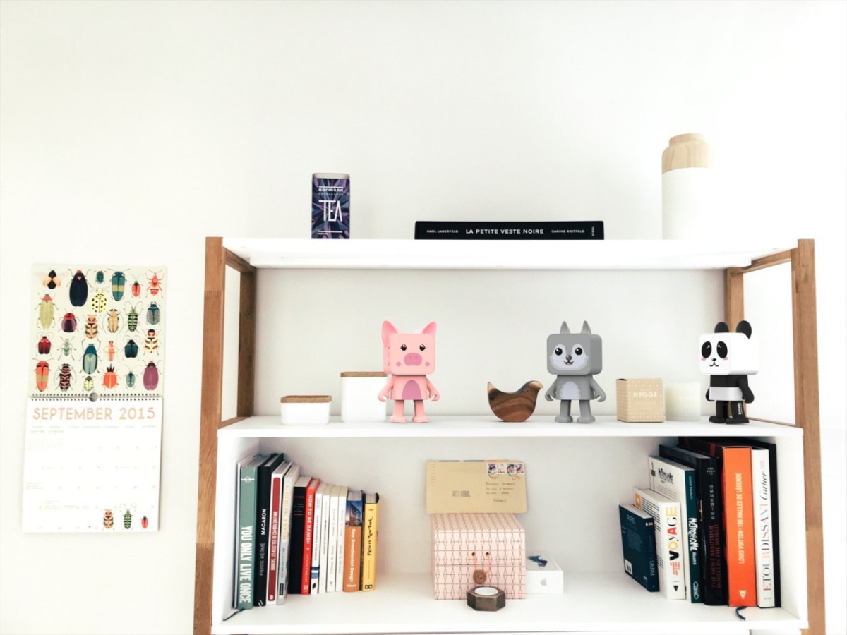 Tańczący głośnik bezprzewodowy świnka na półce obok innych figurek i książek