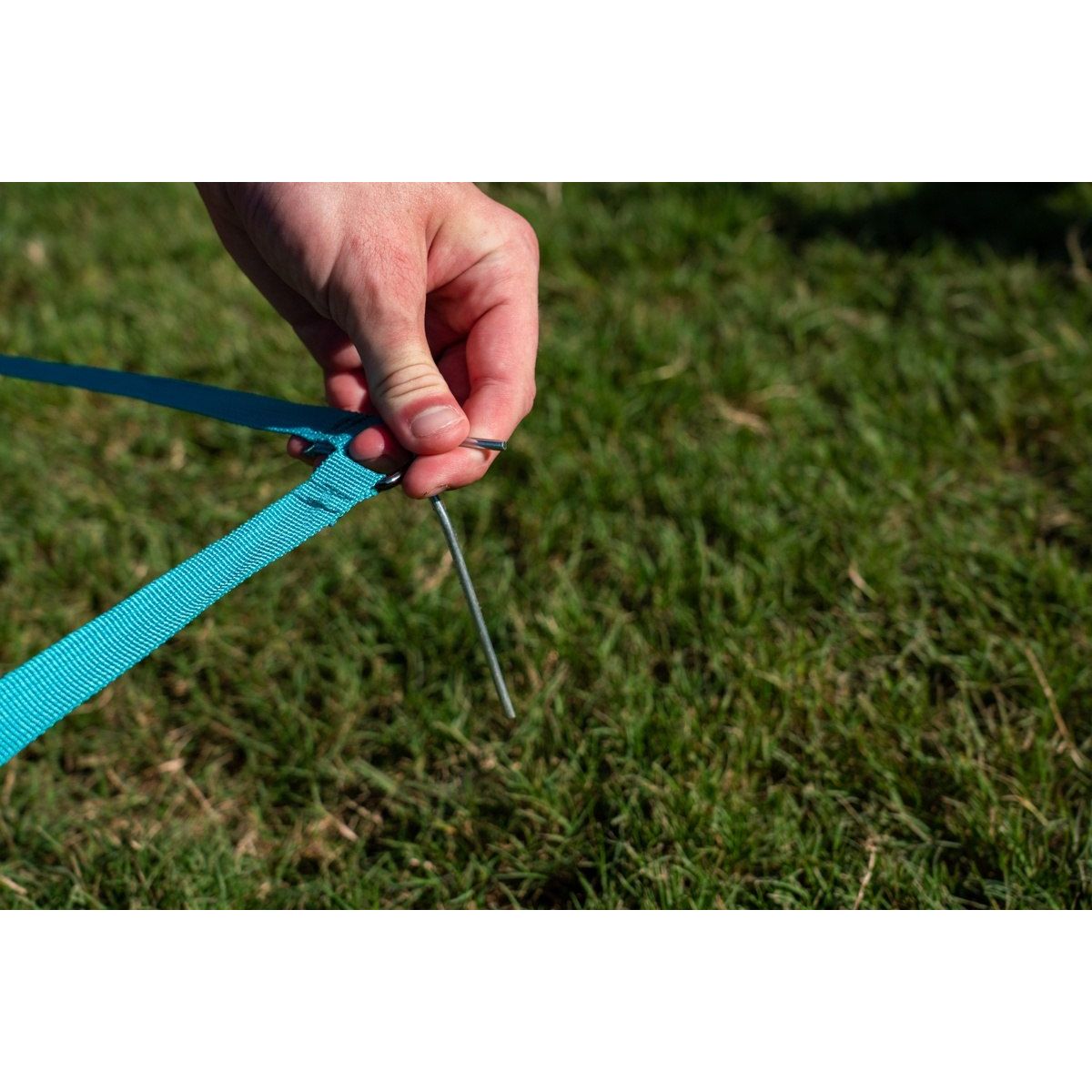 Terenowa gra zręcznościowa dla dzieci Waboba z niebieską taśmą mocowaną do ziemi na trawie