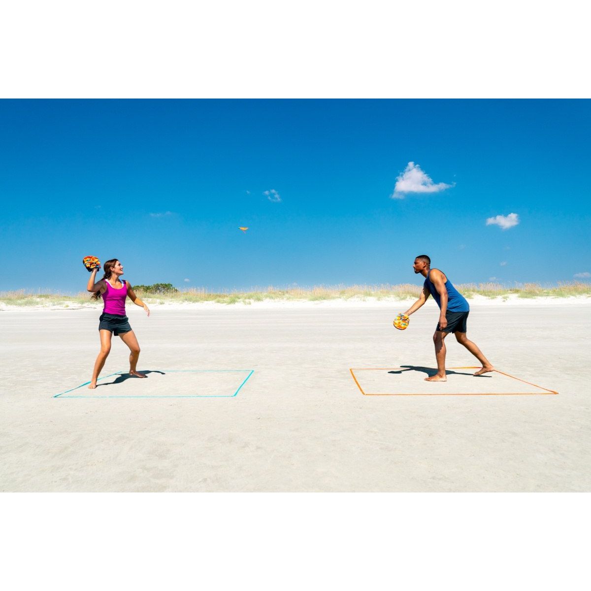 Dwoje dorosłych grających w terenową grę zręcznościową dla dzieci Waboba na plaży pod niebieskim niebem