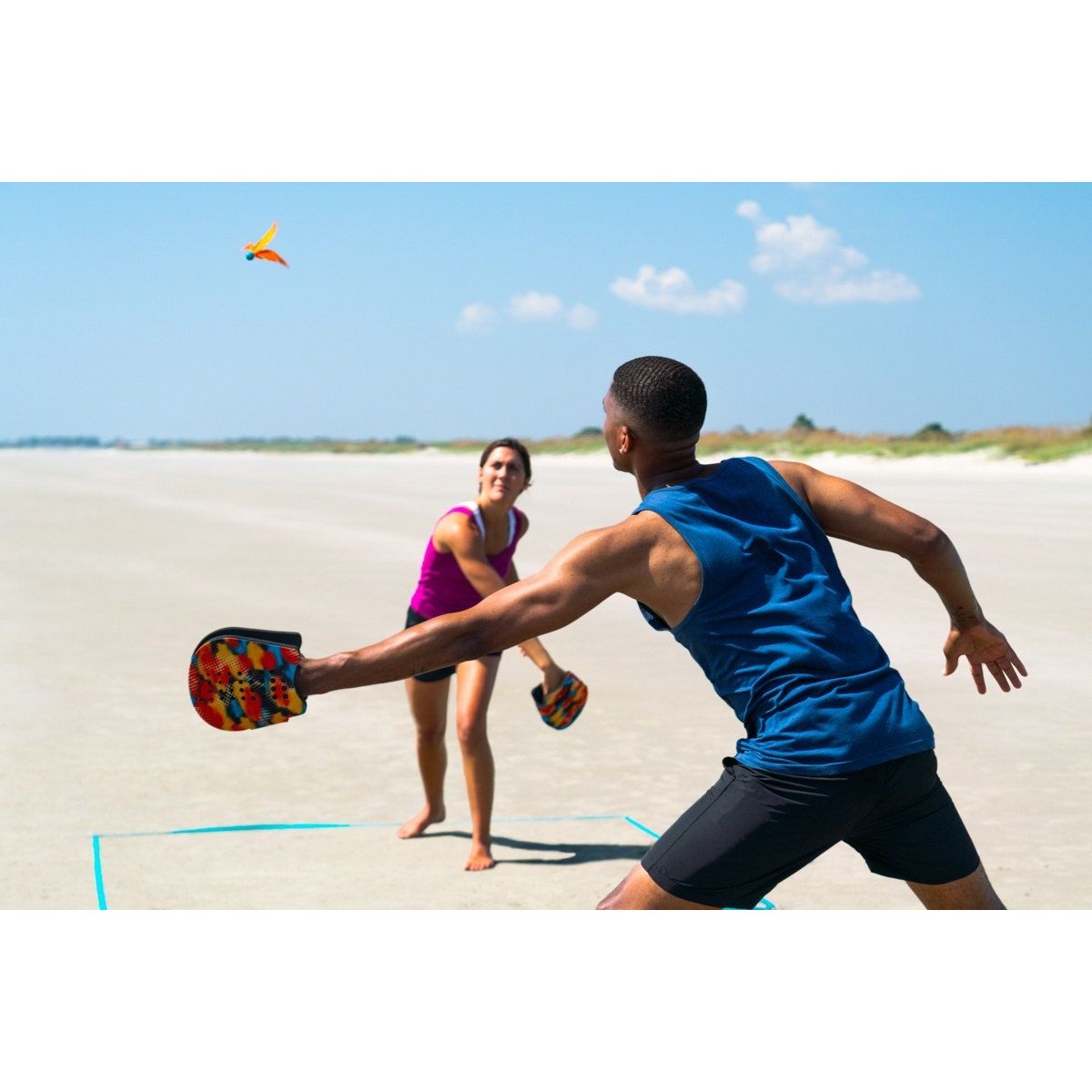 Para gra w terenową grę zręcznościową dla dzieci na plaży z kolorowymi rękawicami i lotką