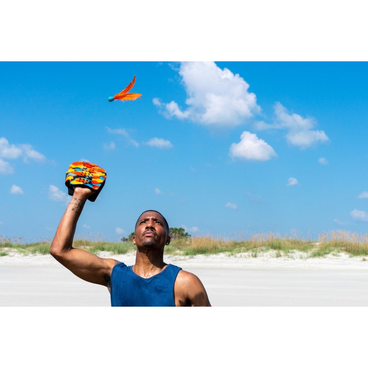 Mężczyzna grający w terenową grę zręcznościową dla dzieci z kolorowym lotką na plaży