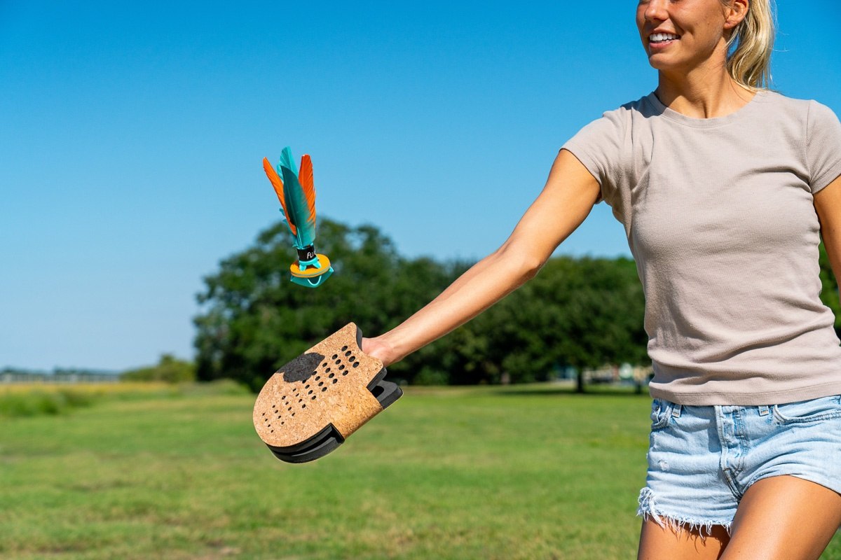 Kobieta grająca na świeżym powietrzu w terenową grę zręcznościową Waboba Voli z rakietką i lotką