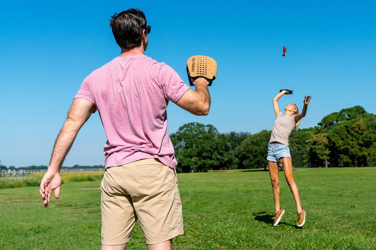 Dwóch graczy gra w terenową grę zręcznościową Waboba Voli na zielonej łące w słoneczny dzień