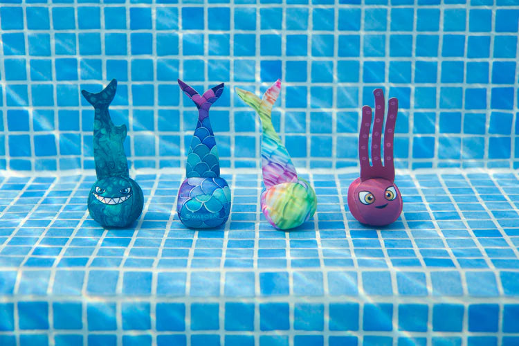 Kolorowe piłki do nurkowania Waboba w kształcie zwierząt ustawione na dnie basenu z niebieską mozaiką
