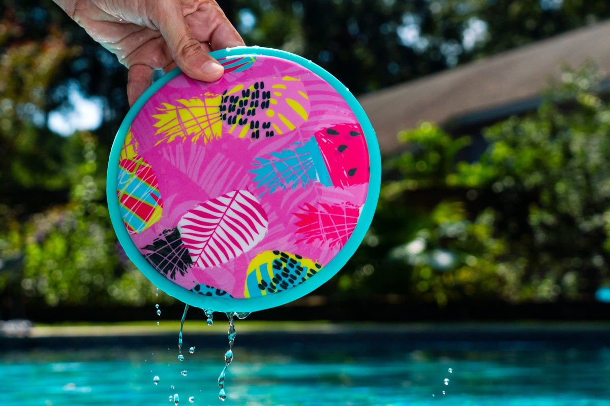 Kolorowe frisbee wodne dla dzieci trzymane nad basenem z kroplami wody spływającymi z obręczy
