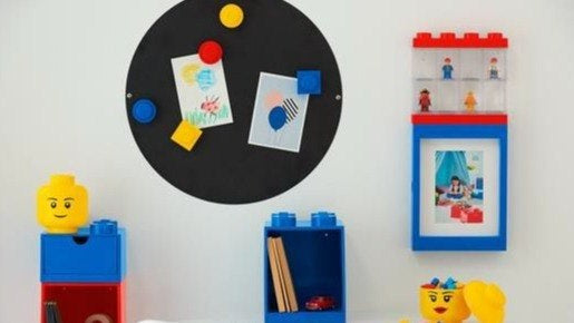 Kolorowe magnesy LEGO czerwone, żółte i niebieskie na czarnej tablicy magnetycznej w pokoju dziecięcym