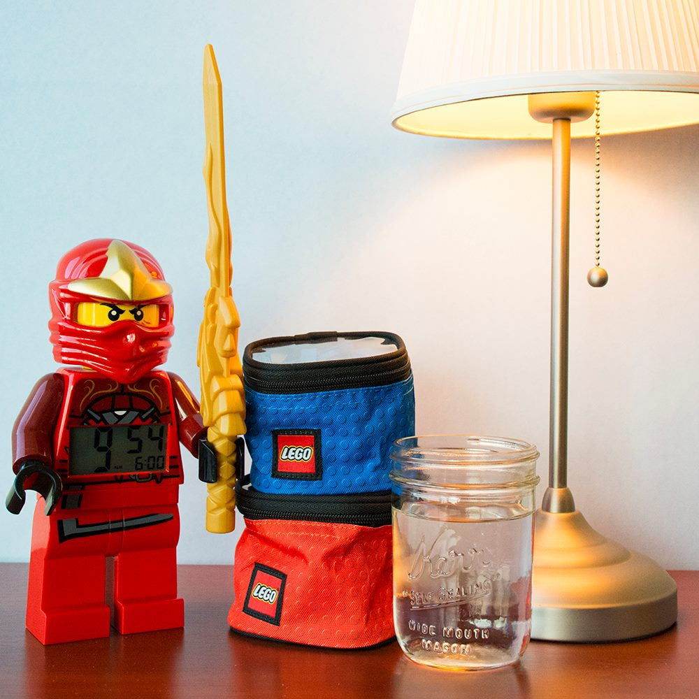 Organizery LEGO na klocki w kolorach niebieskim i czerwonym obok minifigurki LEGO i lampy na stole