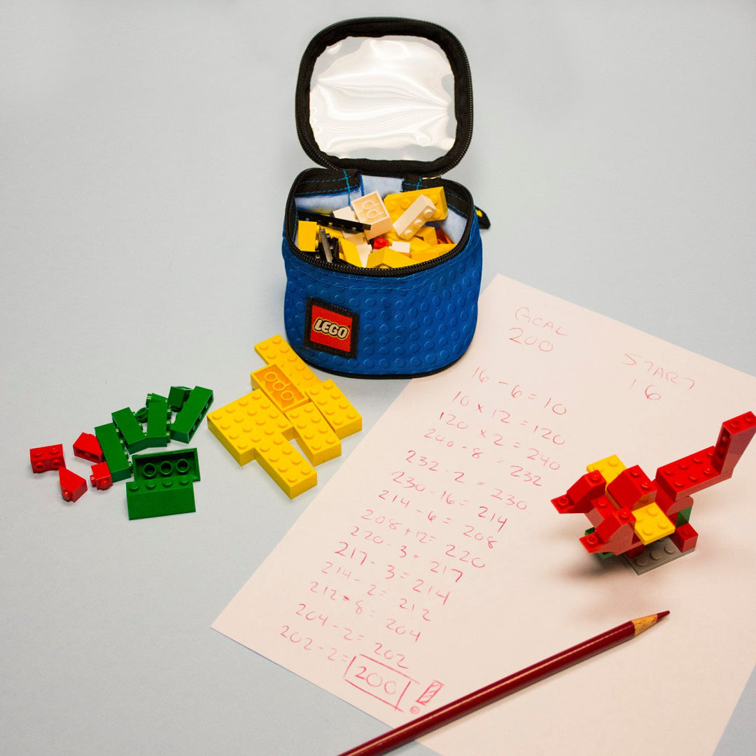 Niebieski organizer na klocki LEGO z otwartą pokrywą i kolorowymi klockami obok na stole z kartką i ołówkiem organizery LEGO na klocki